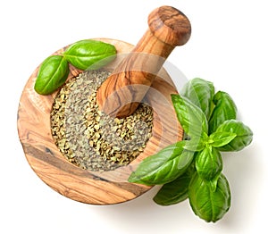 Dried herb, basil leaves in the wooden mortar, isolated on white, top view