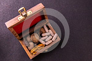 Dried herbs, spices and herbal capsules in a wooden box on black background with copy space. Herbal medicine system concept