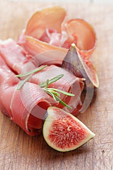 Dried jamon slices with figs on wood table