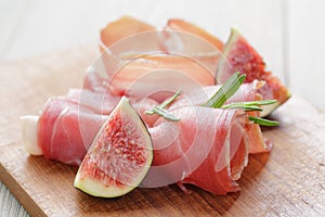 Dried jamon slices with figs on wood table