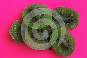 Dried kiwi slices on a pink background.