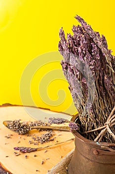 Dried lavender bundle in old metallic pot, with vivid yellow background and copy-space.