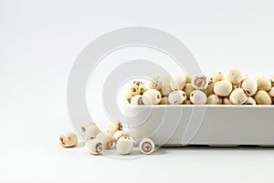 Dried lotus seeds are housed in white ceramic vessels and placed on a white background with copy space