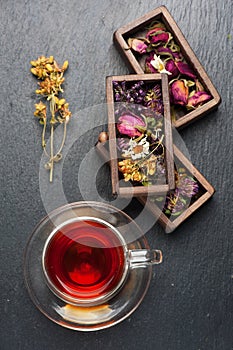 Dried medicinal herbs in wooden boxes and herbal healing tea, top view