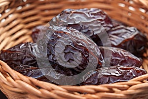 Dried medjool dates in wooden rattan bowl closeup. Arabic dessert treat