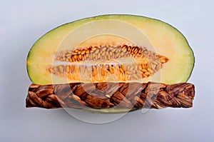 Dried melon in the form of plait on cut melons isolated on white background