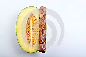 Dried melon in the form of plait on cut melons isolated on white background