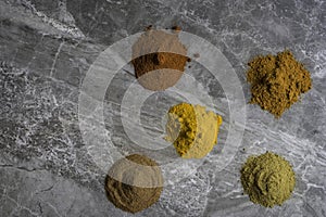 Dried mixed organic spice powders on a marble kitchen worktop background photographed from above