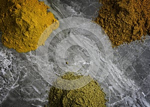 Dried mixed organic spice powders on a marble kitchen worktop background photographed from above