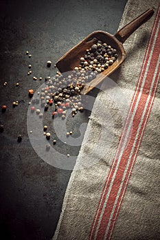 Dried mixed peppercorns spilling from a scoop