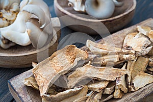 Dried mushrooms and fresh raw oyster mushrooms in craft wooden p