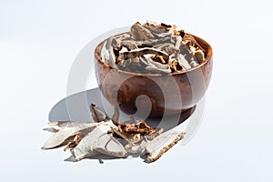 dried mushrooms in a wooden bowl isolated on white