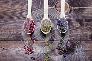 Dried myosotis Mallow flower herbal tea, Green tea and Rose flowers on spoons on wooden table