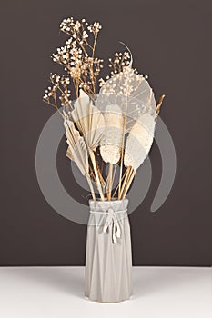 Dried natural flowers bouquet in gray vase with flowers and leaves like palm leaf, skeleton leaf, luffa and flowers