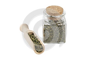 dried nettle herb or in latin Utricae folium in a glass jar and wooden scoop isolated on white background. medicinal healing herbs