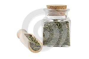 dried nettle herb or in latin Utricae folium in a glass jar and wooden scoop isolated on white background. medicinal healing herbs