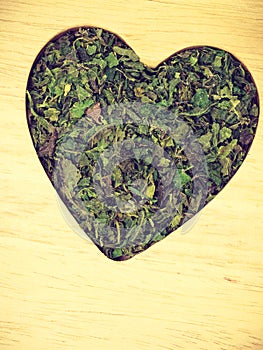 Dried nettle leaves heart shaped on wooden surface