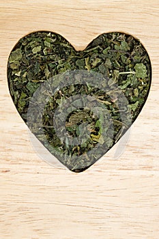 Dried nettle leaves heart shaped on wooden surface