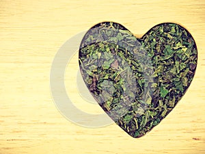 Dried nettle leaves heart shaped on wooden surface