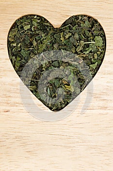 Dried nettle leaves heart shaped on wooden surface