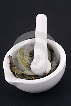 Dried nettle leaves in a mortar with a pestle close-up on a black background