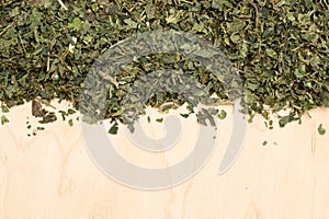 Dried nettle leaves on wooden board with copy space