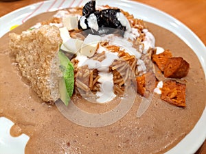 Dried noodle dish with beans, chipotle and natural cream, accompanied with cheese, avocado and pieces of crusty bread