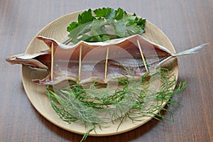 Dried omul on the wooden plate, decorated with verdure