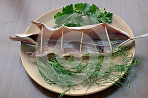 Dried omul on the wooden plate, decorated with verdure