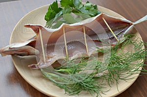 Dried omul on the wooden plate, decorated with verdure