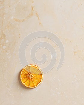 Dried orange slice on a light stone background
