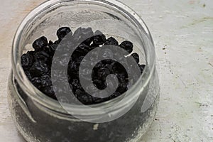 Dried organic Blue berries in a jar on a white background with selective focus