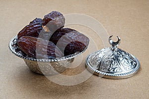 Dried organic sweet date fruits in a silver traditional bowl with ornate half moon cap