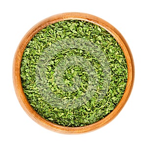 Dried parsley in wooden bowl over white photo