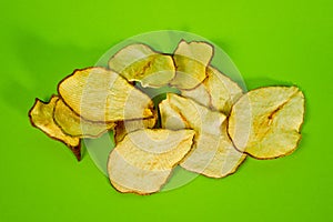 Dried pear chips, closeup shot on a green background. Background for a healthy diet