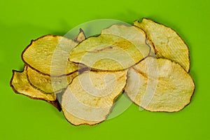 Dried pear chips, closeup shot on a green background. Background for a healthy diet