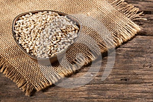 Dried pearl barley in a wooden bowl - Hordeum vulgare