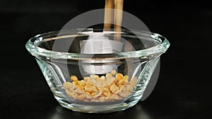 Dried peas are poured on glass bowl on black background. Close up.
