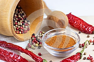 Dried peppercorn mix in the mortar with pestle, dry chili pepper powder for cooking on light wooden cutting board background