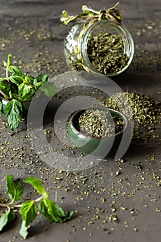 Dried peppermint in a bowl and a bunch of fresh mint, on gray background