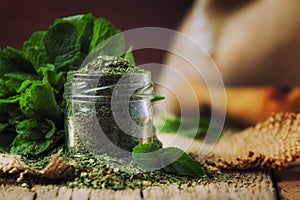 Dried peppermint in a glass jar and a bunch of fresh mint, vintage wood background, selective focus