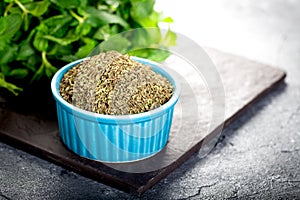 Dried peppermint in a white bowl and a bunch of fresh mint, on wooden background. Food background
