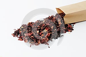 Dried petals pomegranate flowers tea. Poured out of a paper bag on a white background. Flower drink, healthy food