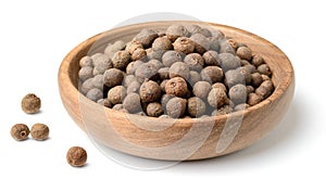 Dried pimento berries in the wooden plate, isolated on white background