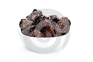 Dried plums in white bowl isolated on white background.