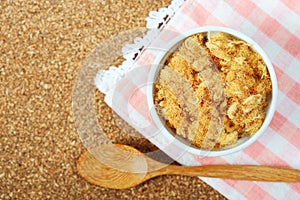 dried pork floss in white cup with wooden spoon on corkboard background.