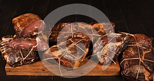Dried Processed Beef Jerky tied with string on wooden board against black background.