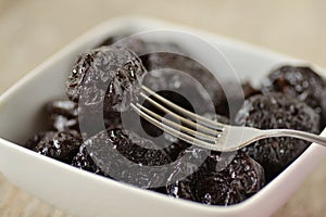Dried prunes in a bowl with a fork