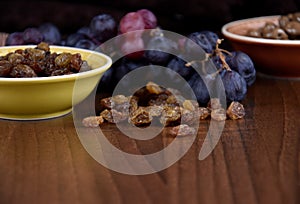 Dried raisins with a bunch of grapes on a wooden background stock images