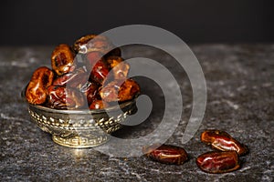 Dried raisins of grapes and dates in a medium-sized cup.